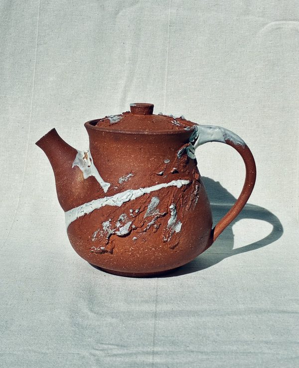 Red stoneware teapot with a white glaze pour